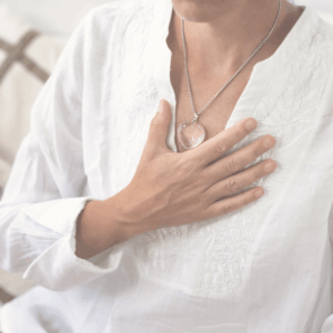 Frau legt eine Hand auf ihr Herz – Symbol für Selbstannahme und Akzeptanz