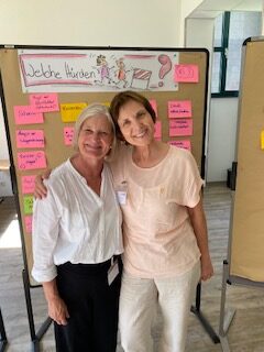 Zwei Frauen aus der Selbsthilfe vor einer Pinwand