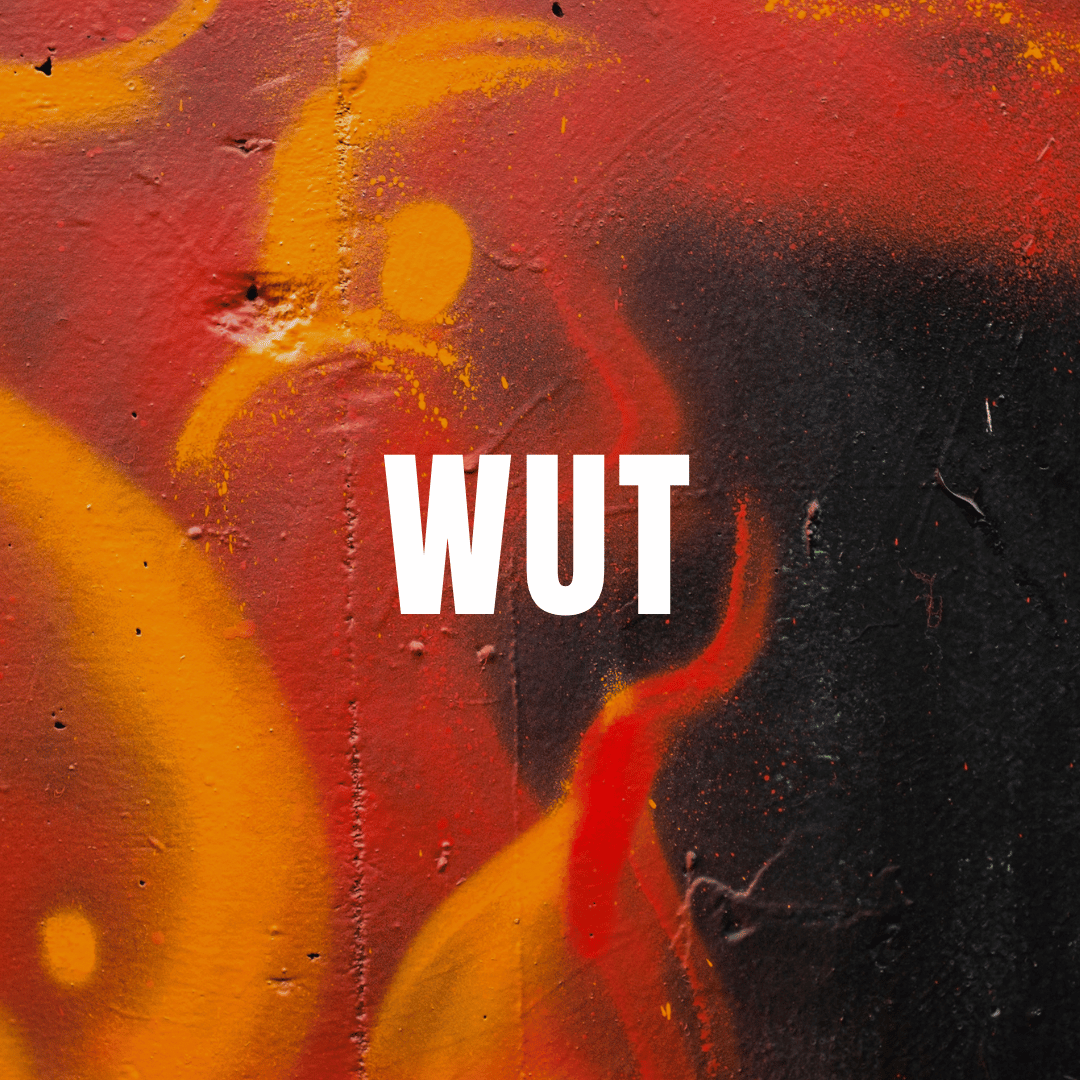 Abstraktes Graffiti in Rot, Orange und Schwarz auf rauem Beton. In der Mitte steht groß in weißer Schrift das Wort WUT.